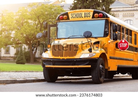 Shot of retro-styled yellow school bus with extended red stop sign standing still on serene road, empty vehicle with no driver awaiting children to boarding, transportation concept, copy space Royalty-Free Stock Photo #2376174803