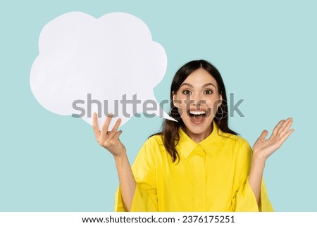 Lovely emotional Latin woman holds communication bubble in her hand symbolizing power of expression and connection suggests to place your advertising content isolated on blue background Royalty-Free Stock Photo #2376175251