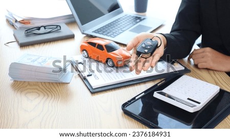 Car salesman holds keys at car dealership in office