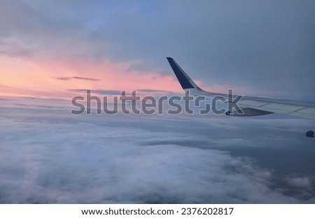 A Scenic View of the Wings of a aero plane flying above the clouds. Travelling by aero plane during sunset. Royalty-Free Stock Photo #2376202817