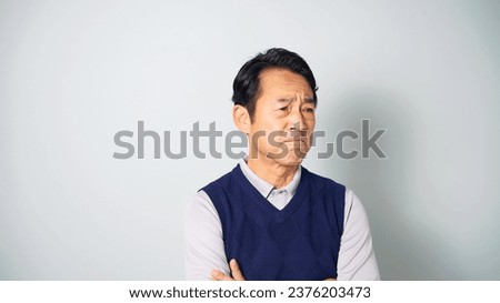 Irritated middle-aged Asian man wearing casual wear in white background. Royalty-Free Stock Photo #2376203473