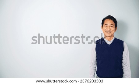 A middle-aged Asian man wearing casual wear smiling in front of a white background. Royalty-Free Stock Photo #2376203503