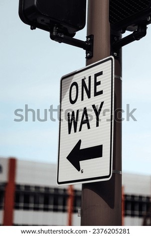 A "one way" sign on a black and white street signboard