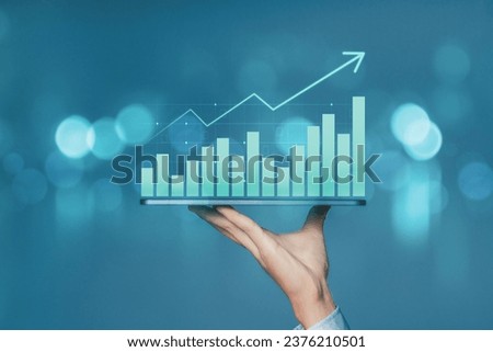 Businessman holding smartphone with business chart growth graph and and increase of chart positive indicators business. Analysis of investment strategies and economic trends. Royalty-Free Stock Photo #2376210501