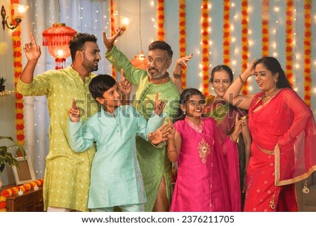 Group of family members dancing together during diwali festive celebration gathering at home - concept of entertainment, Holiday reunion and enjoyment Royalty-Free Stock Photo #2376211705