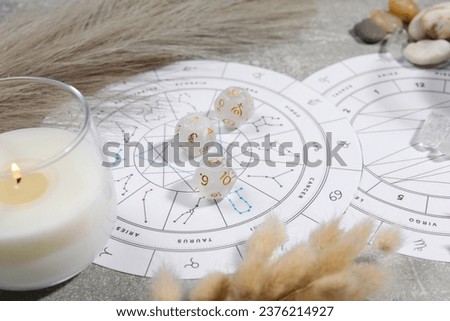 Zodiac wheel, natal chart, burning candle, astrology dices and stones on grey table, closeup Royalty-Free Stock Photo #2376214927