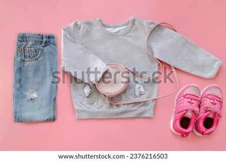 Warm jumper,sweater,sneakers,jeans pants,purse,little bag.Set of baby children's clothes,clothing for spring,summer,autumn on pink background.Casual fashion girls kids outfit.Flat lay,top view.