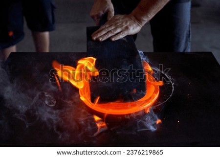 Crop male glassmiths standing at metal workbench and forming burning liquid glass while working in workshop together Royalty-Free Stock Photo #2376219865