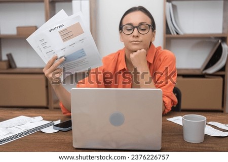 Bored at home, a woman tackles domestic bills using a computer app, while a bank customer takes care of credit insurance paperwork Royalty-Free Stock Photo #2376226757