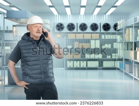 Man warehouse specialist. Worker stands in industrial refrigerator. Freezer in supermarket warehouse. Man storekeeper speaks on phone. Guy inside warehouse refrigerator. Freezing equipment