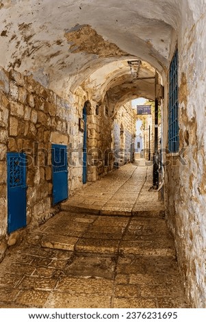 A narrow cobblestone street or alley in the Jewish quarter of Israel's highest elevation city, Tzafet (Safed). Sign Translation: Rabbi Moshe Elsheich synagogue. Royalty-Free Stock Photo #2376231695
