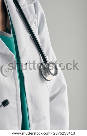 Crop anonymous doctor in white medical uniform with professional stethoscope at work on light background Royalty-Free Stock Photo #2376233413
