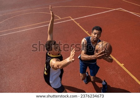 Two athletes playing basketball outdoors.