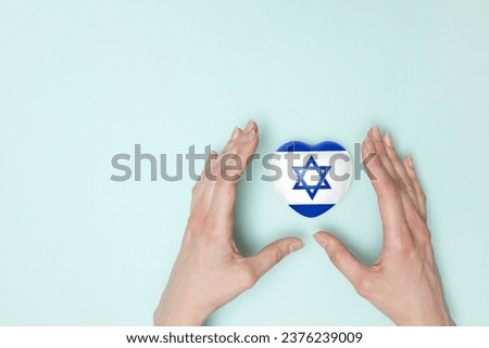 Heart with print of Israel flag in female hands. Flat lay.
