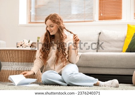 Beautiful redhead woman reading book at home