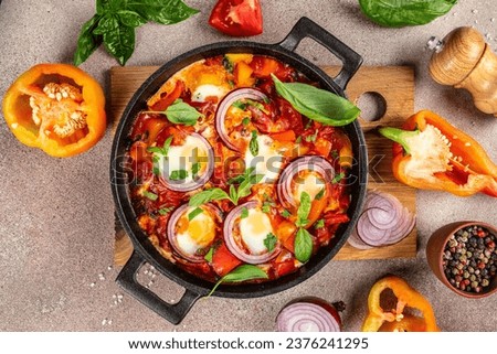 Shakshuka. Fried eggs with vegetables in a cast iron pan, traditional middle eastern traditional dish place for text, top view, Royalty-Free Stock Photo #2376241295