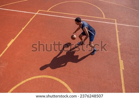 Sporty player guy training basketball at outdoor court.