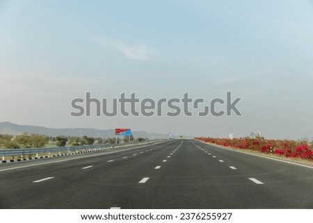 The highway bordered by lush greenery and mountains, India's Delhi-Mumbai Expressway Royalty-Free Stock Photo #2376255927