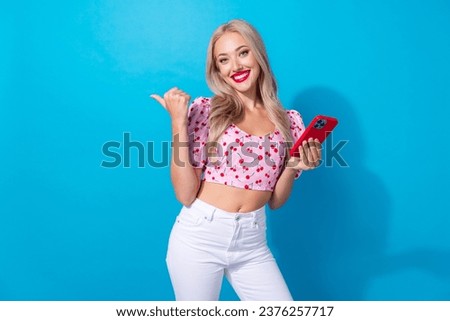 Photo portrait of pretty young girl palm gadget point empty space wear trendy pink cherry print outfit isolated on blue color background