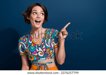 Photo of young charming woman wear glamour top pointing finger copy space interested showing promo code isolated on blue color background