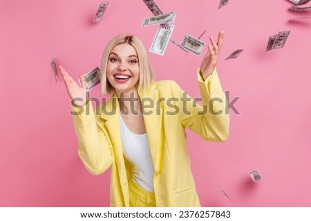 Photo of astonished successful pretty person flying falling dollar bills isolated on pink color background