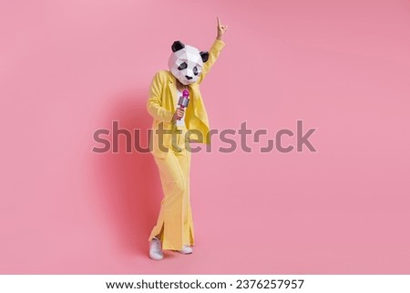Full length of cool carefree person 3d panda mask point finger sing microphone empty space isolated on pink color background