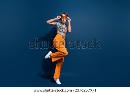 Full body photo of pretty young girl touch sunglass dancing have fun wear trendy flared pants jeans isolated on dark blue color background