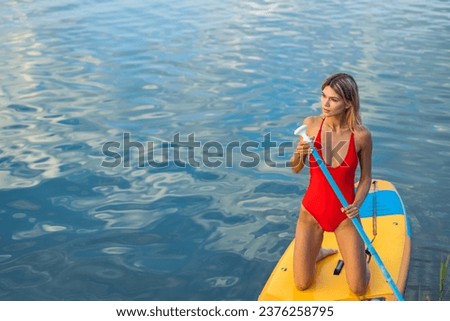 Beautiful blonde woman on SUP board on vacation.