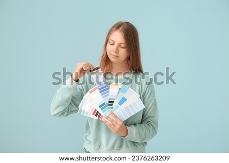 Young woman with color samples on light blue background