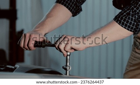 An auto mechanic is working on a car engine in a car workshop. Close-up ratchet wrench Royalty-Free Stock Photo #2376264437