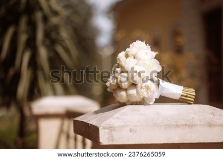 Elegant white rose bouquet on stone pillar in garden. Concept for wedding or anniversary celebration, or romantic gift. Roses symbolize purity and love, and the pillar adds a touch of classic style.