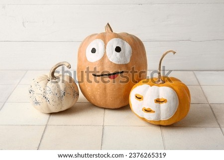 Different painted Halloween pumpkins on white tiled table
