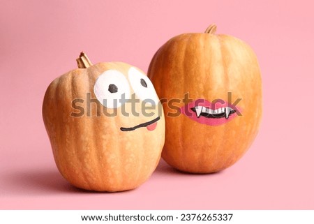 Funny Halloween pumpkins with drawn faces on pink background