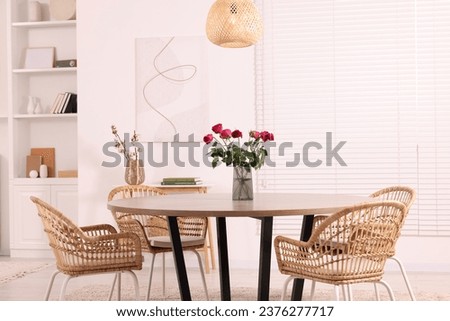 Chairs and table with vase of red rose flowers in dining room. Stylish interior