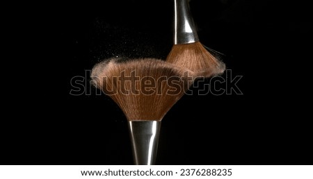 Make-up Brush spreading blush powder on black background