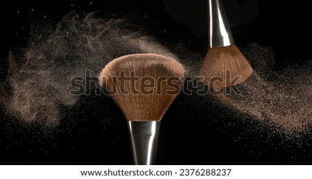 Make-up Brush spreading blush powder on black background