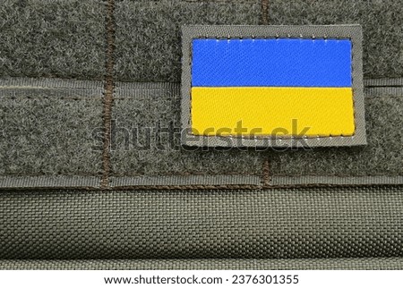 Chevron of  Armed Forces of Ukraine,  with  flag of Ukraine on background of military uniform, green camouflage. Ukrainian Armed Forces