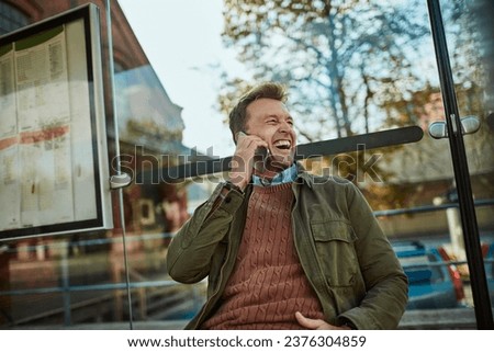 Middle aged man talking on his smartphone at the bus stop