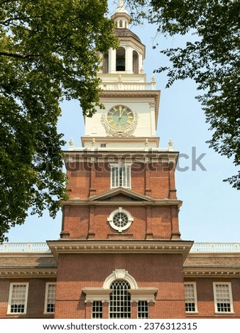 The clock tower of independence hall through the trees of independence square in Philadelphia on a summers day