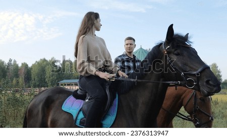 Training hobby during the holidays. Horseback riding at the farm, equestrian club. A young family rides horses. Riding lessons, a young couple ride horses in a paddock at a ranch. Royalty-Free Stock Photo #2376313947