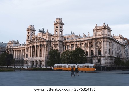 Old Budapest tram and couple pass through Kossuth Lajos Square in front of Igazságügyi palota at sunset in summer Royalty-Free Stock Photo #2376314195