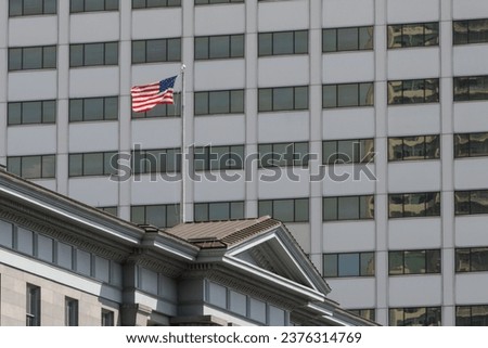 American flag flys above the period US Customs House on Canal Street, New Orleans, on a summers day with a brutalist tower block behind it