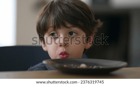 Contemplative close-up child's face lost in thought while chewing food, small boy gazing in the distance in deep mental reflection while eating