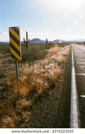 A vertical view of the Arizona 86 highway in Pima County with a hazard sign and cactus in the distance