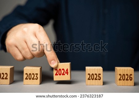 The coming of 2024. The man determines the next year. Reflecting on past achievements and experiences, looking forward. Embracing new trends, making forecasts, setting plans for coming future. Royalty-Free Stock Photo #2376323187