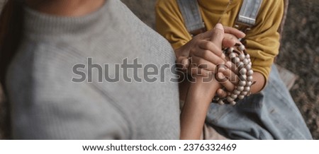 Mother and daughter putting their hands together to pray for God's blessings.