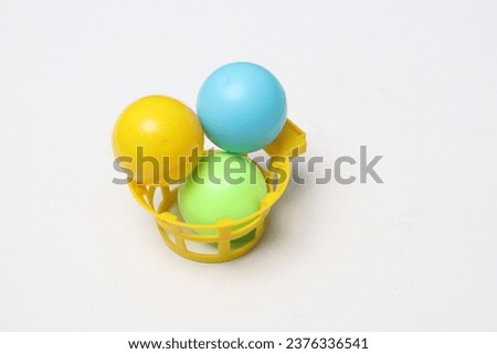 
Three small balls, each yellow, green and blue. There is also a small yellow plastic basket, a children's toy. Isolated white.