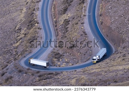 Two trucks take a dangerous curve on a deserted mountain road in Cuesta del Lipán, Jujuy, Argentina. Photo with space for text. Royalty-Free Stock Photo #2376343779