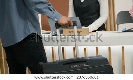 Guest travelling with trolley bags at hotel, receiving access key card at reception after long flight. African american tourist on vacation at five star holiday resort. Close up. Handheld shot. Royalty-Free Stock Photo #2376350681