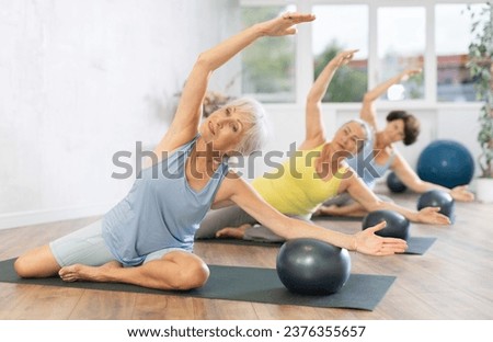 Group of elderly women practicing pilates with soft ball in fitness studio Royalty-Free Stock Photo #2376355657